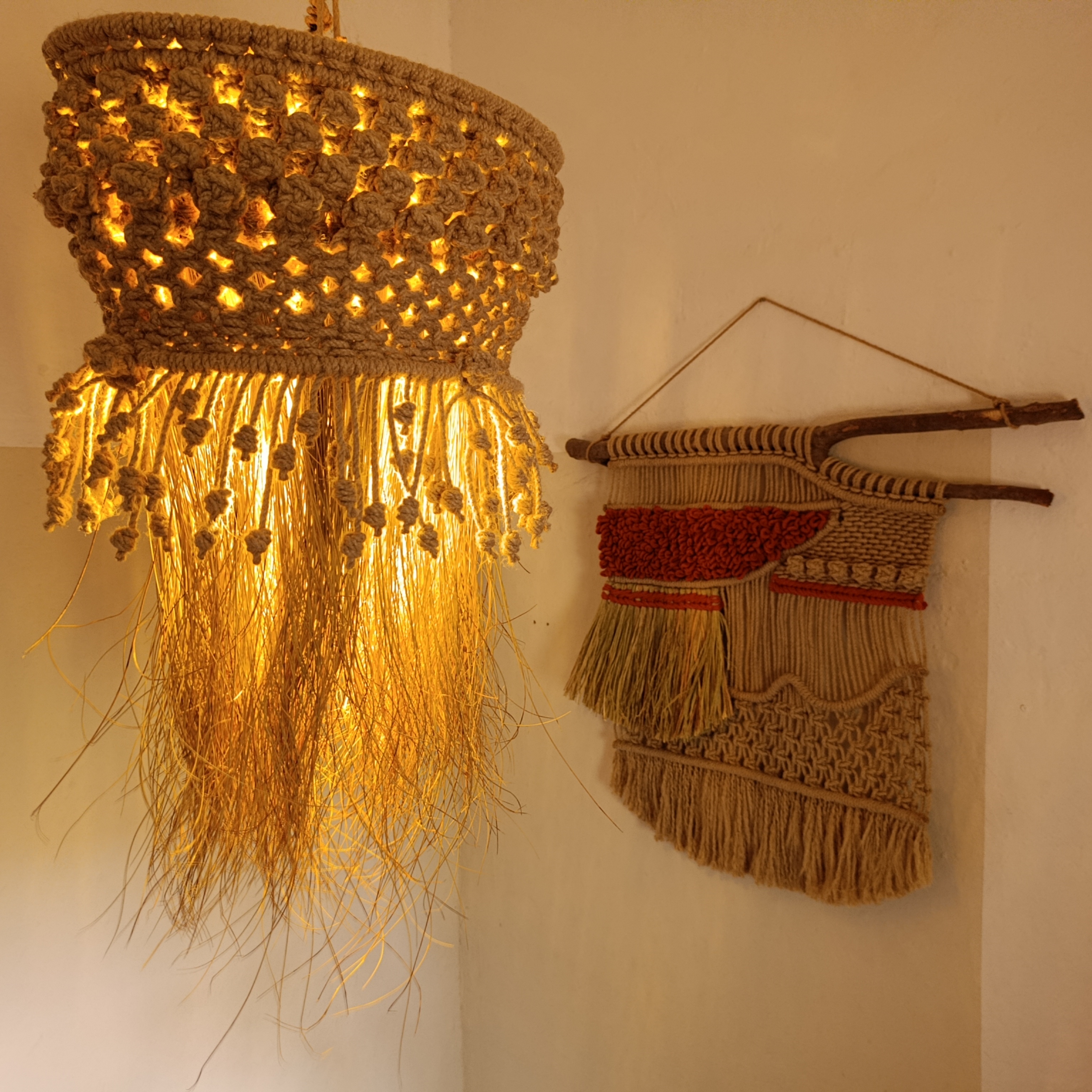 A product photo including both Sueños de Palmeras and Campo en Julio, the lamp SDP is illuminated and casts a shadow on CEJ and the wall.